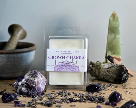 Crown Chakra Wax Melt in a clear container on a wooden surface with crystals, dried herbs,  smudge bundles, and a small mortar & pestle.