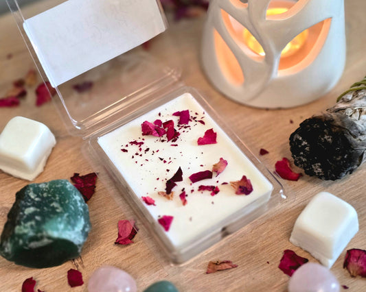 Heart Chakra Wax Melt with dried herbs in a clear container on a wooden surface with crystals, wax melt cubes, and a small wax melter.