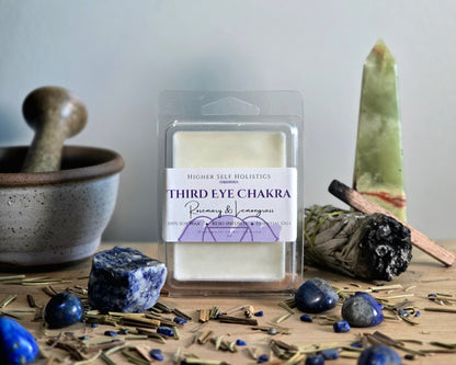 Third Eye Chakra Wax Melt in a clear container on a wooden surface with crystals, dried herbs,  smudge bundles, and a small mortar & pestle.